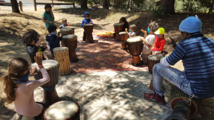 children campers in a drum circle outside