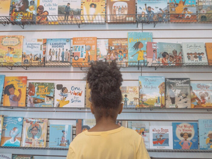 Child stands in front of collection of books