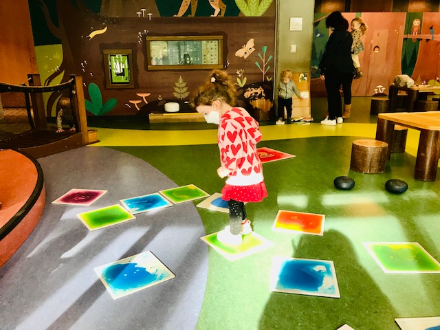 child jumping on colored floor tiles