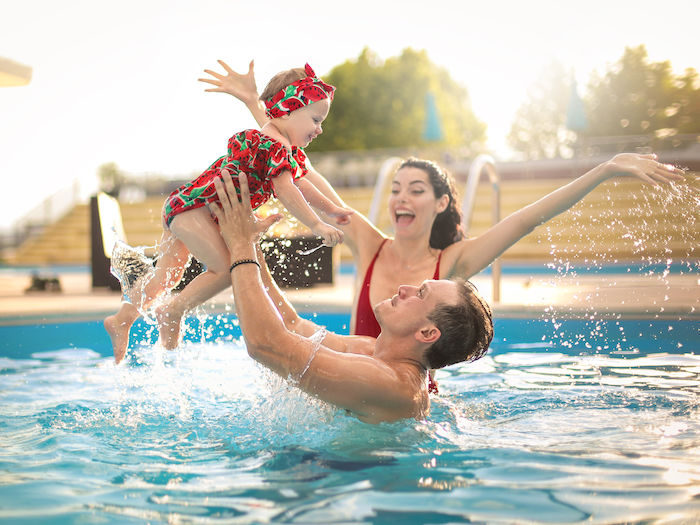 swimming girl with parents at pool