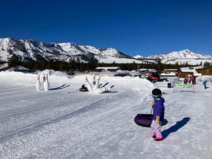 Child pulls tube up hill in snow