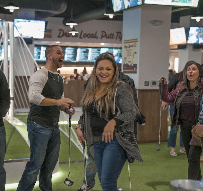 adults playing indoor mini golf