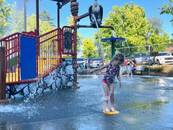 Child standing on water fountain at spray park