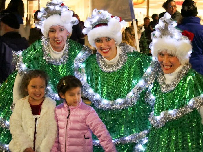 three costumed christmas tree people and two young children smiling