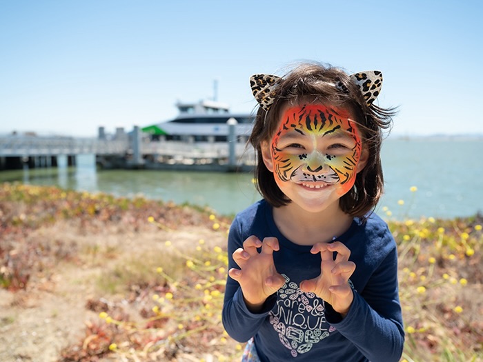 child with painted face also ferry in the distance